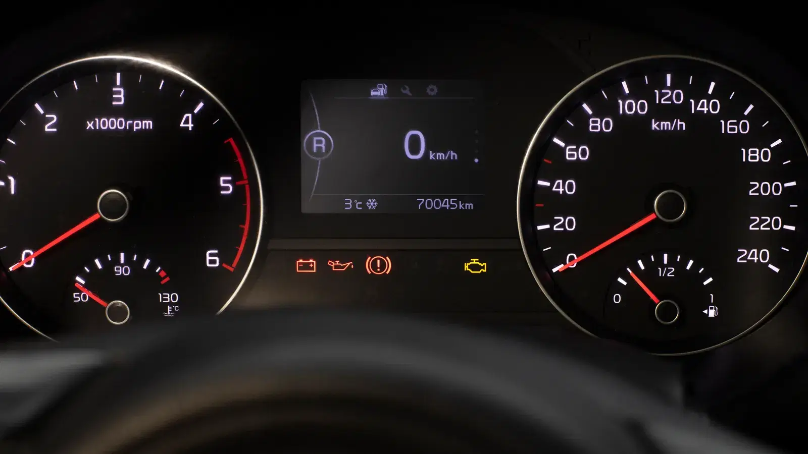Instrument cluster at night with the service spanner symbol and warning lights showing between the rev counter and speedometer