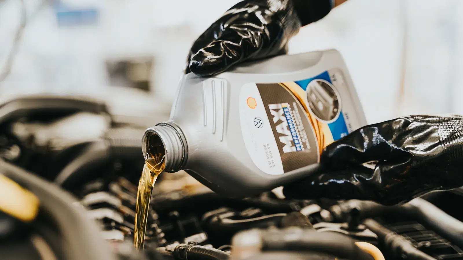 Gloved hands pouring manufacturer-spec oil into a European engine