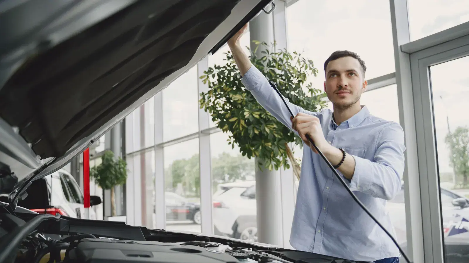 A buyer raising the bonnet to inspect a used car before purchase