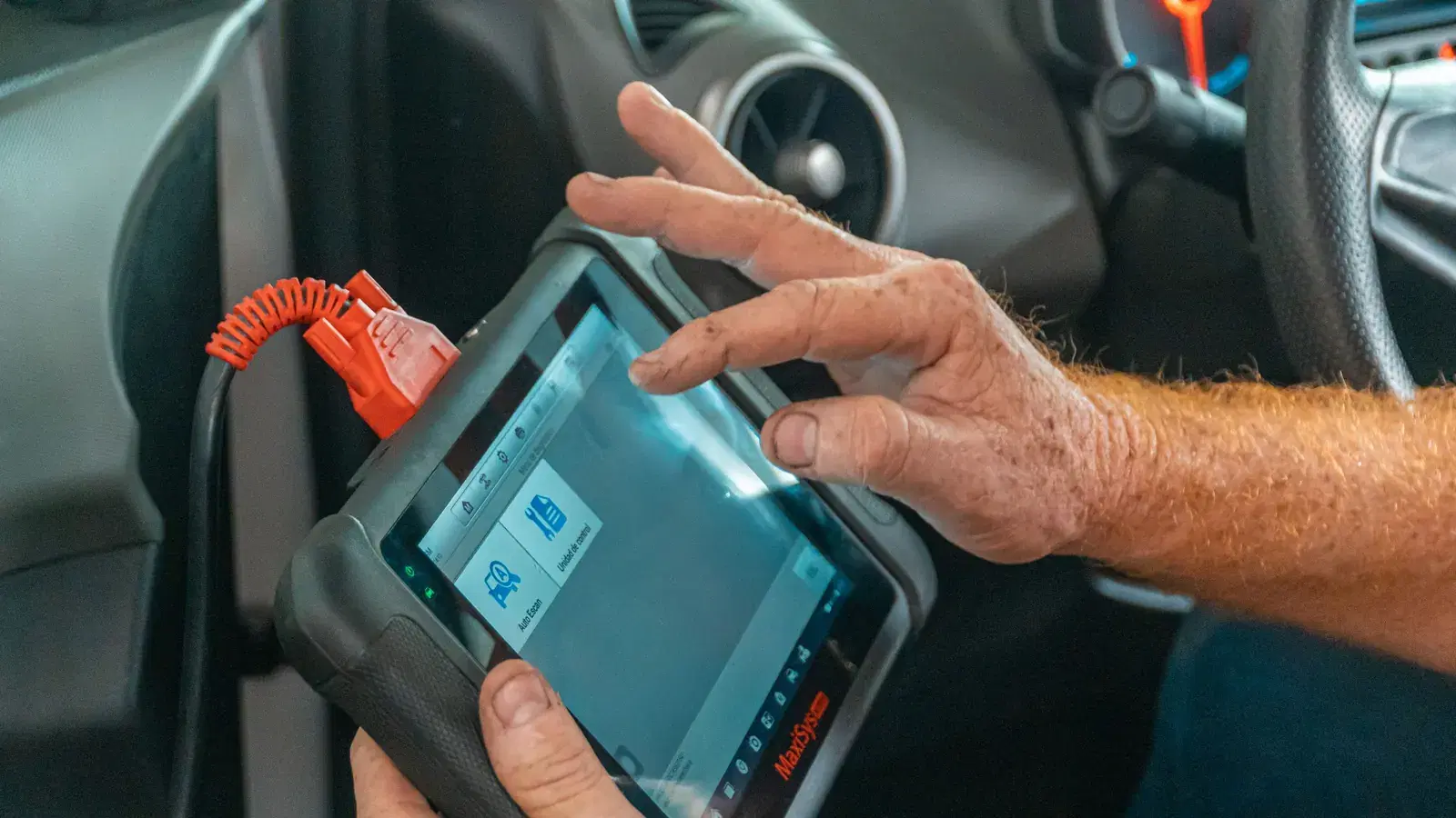 Technician working through a diagnostic scan tool plugged into a car's OBD port