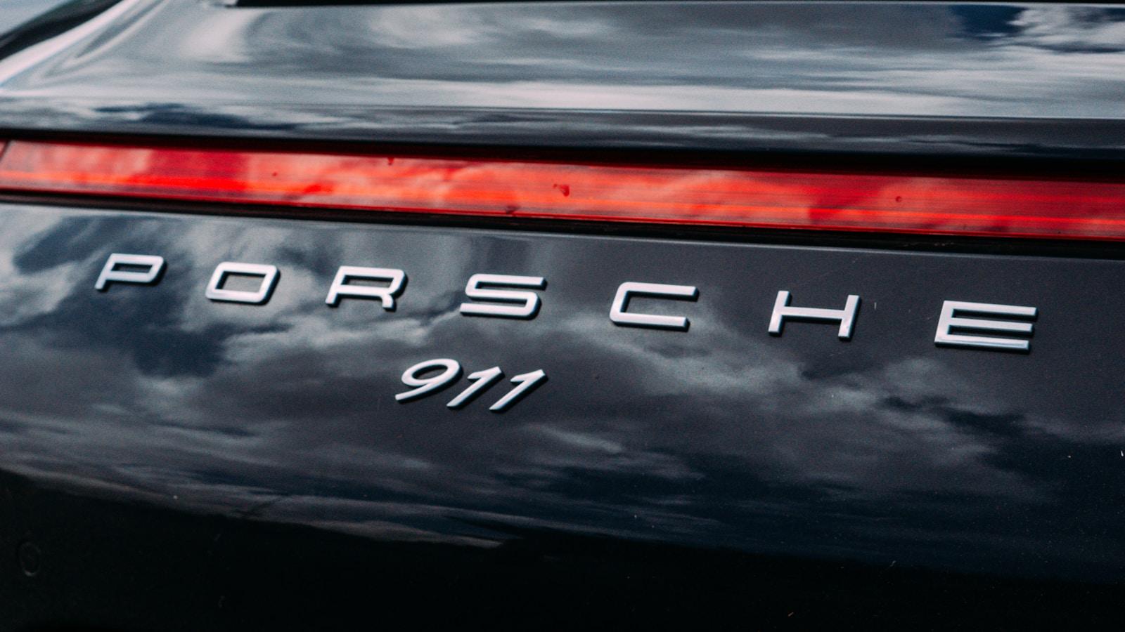 PORSCHE 911 badge on the tailgate of a dark 911, above the rear light bar
