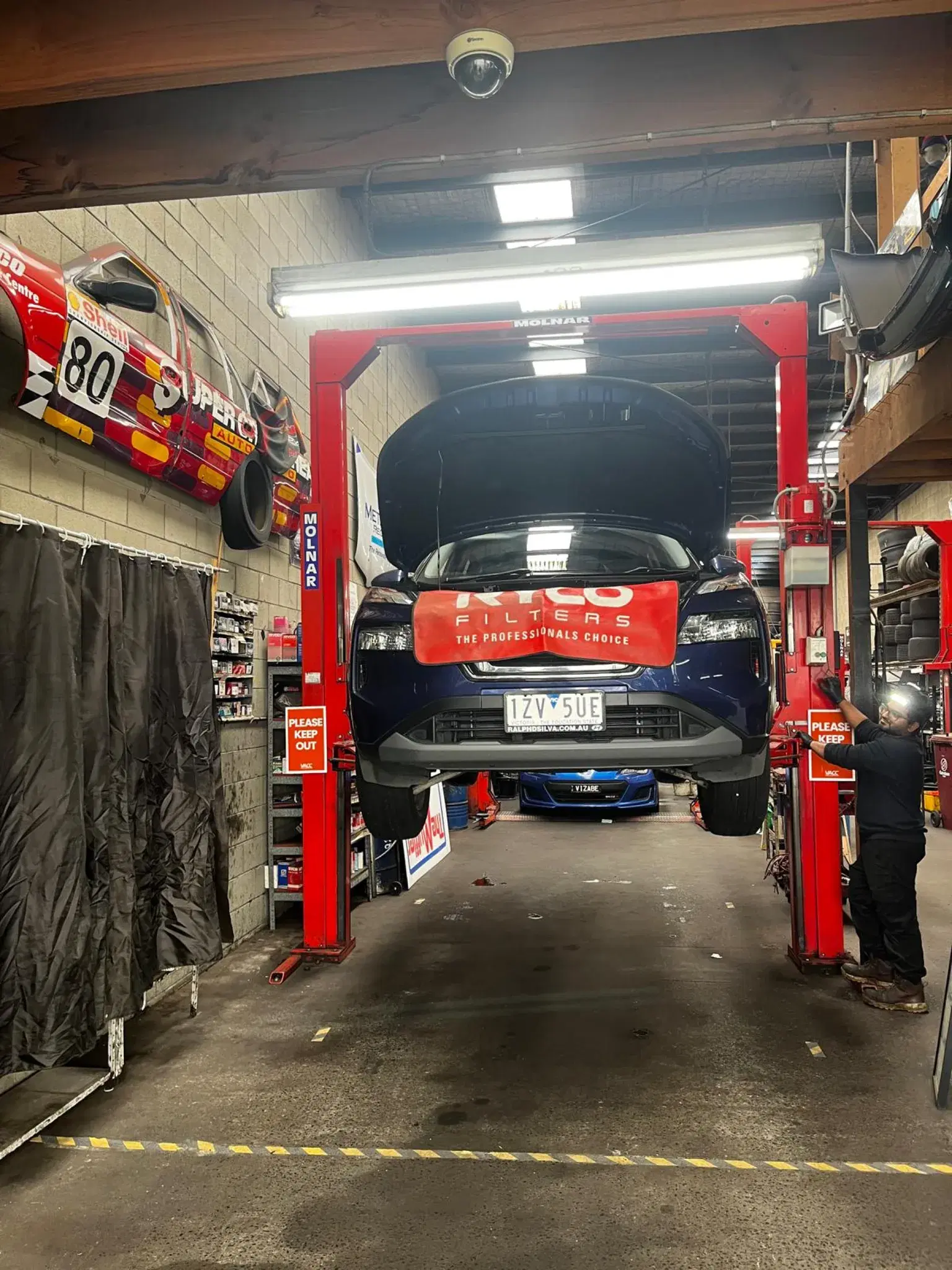 SUV raised on a hoist with the bonnet open in the service bay
